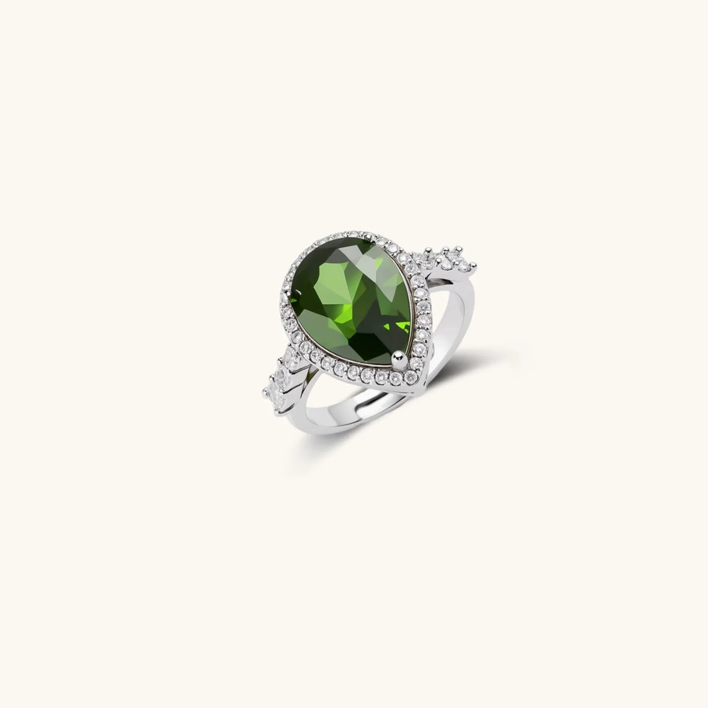 White gold plated jewelry set with green teardrop gemstones and cubic zirconia halos on cream background.