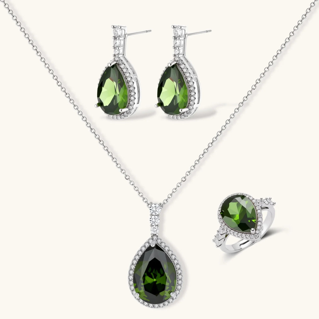 White gold plated jewelry set with green teardrop gemstones and cubic zirconia halos on cream background.