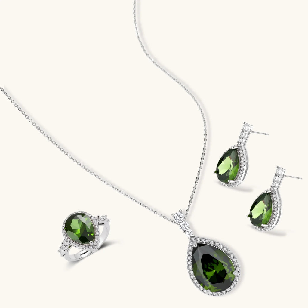 White gold plated jewelry set with green teardrop gemstones and cubic zirconia halos on cream background.