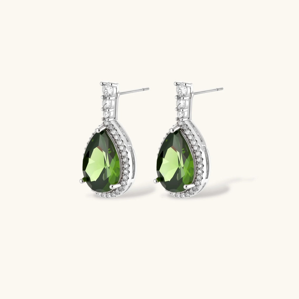 White gold plated jewelry set with green teardrop gemstones and cubic zirconia halos on cream background.