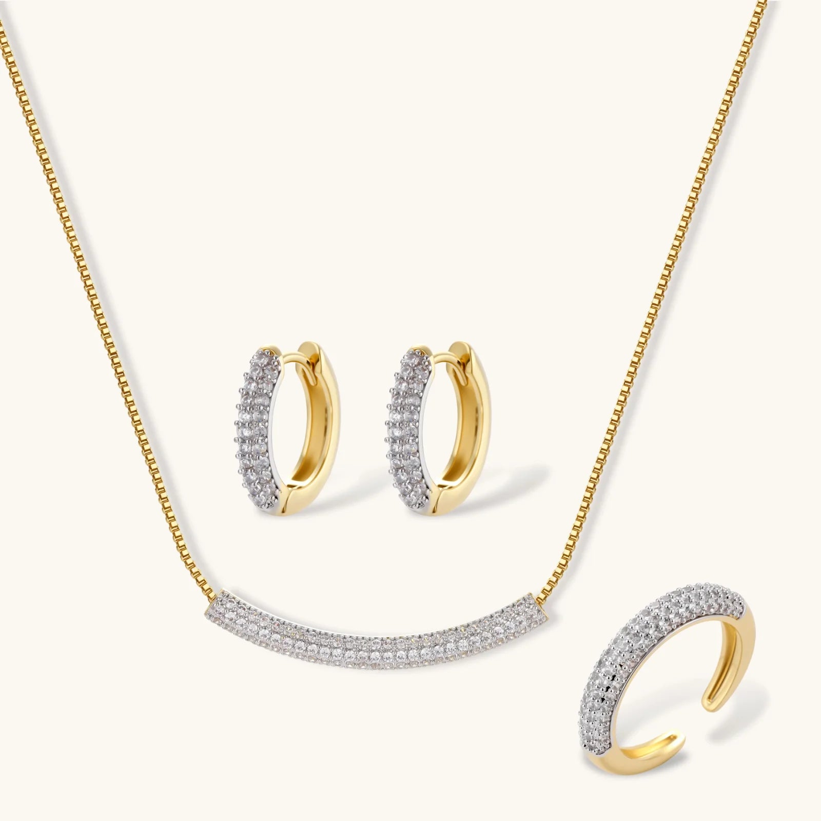 Gold-plated curved necklace, hoop earrings, and adjustable ring with pavé cubic zirconia stones on cream background.