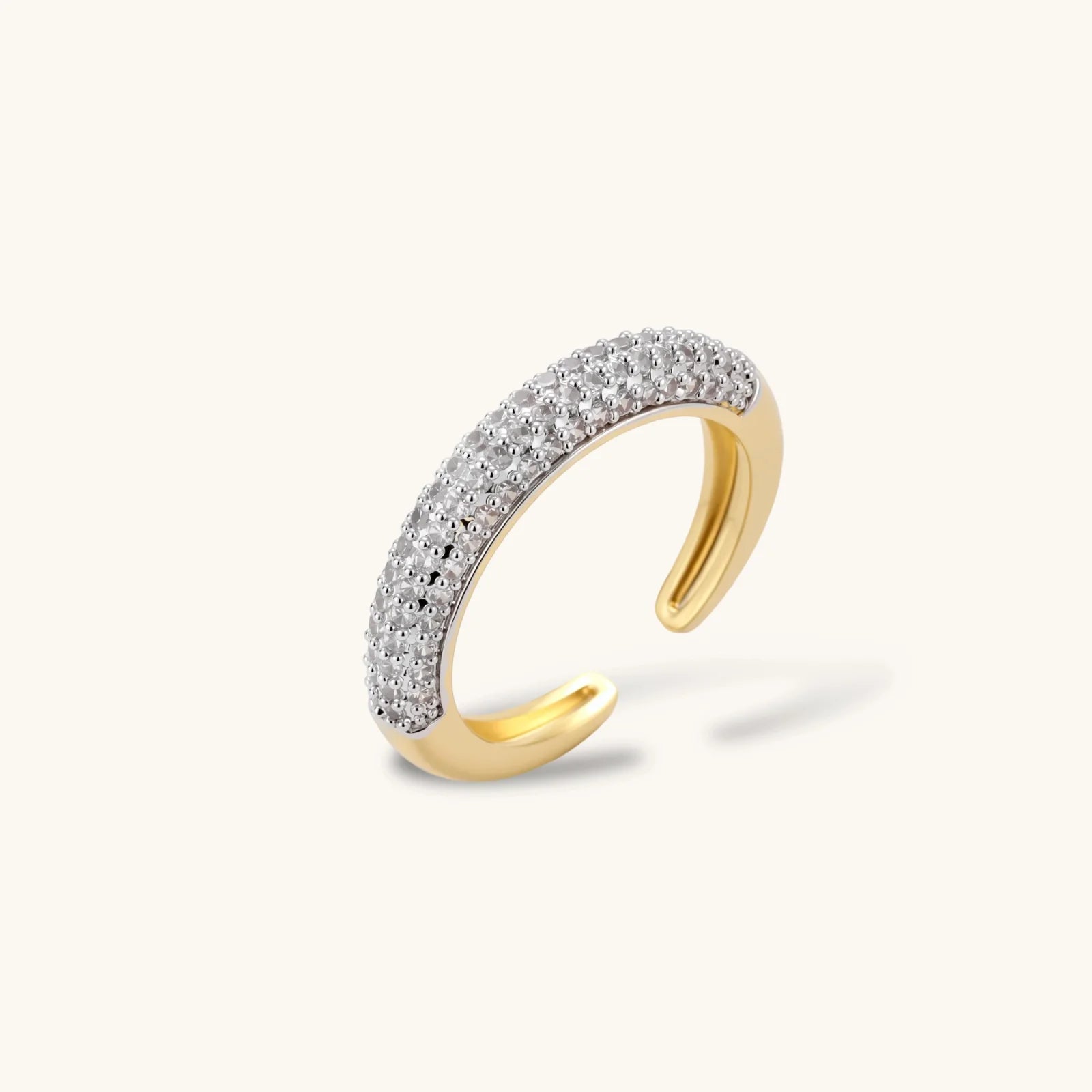 Gold-plated curved necklace, hoop earrings, and adjustable ring with pavé cubic zirconia stones on cream background.