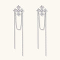 White gold plated baroque cross stud earrings with long cascading zirconia chains on cream background
