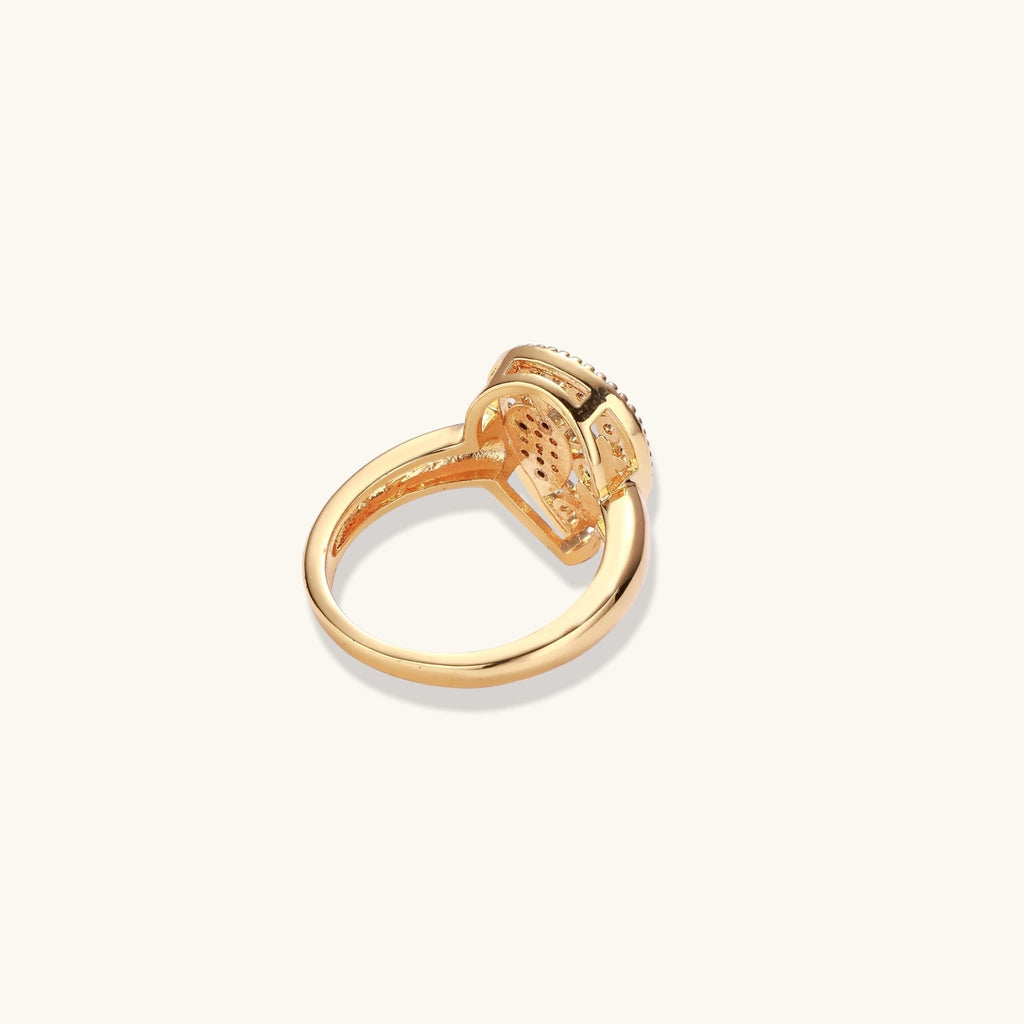 Teardrop-shaped gold-plated ring with turquoise enamel flowers and crystal pavé detail on cream background