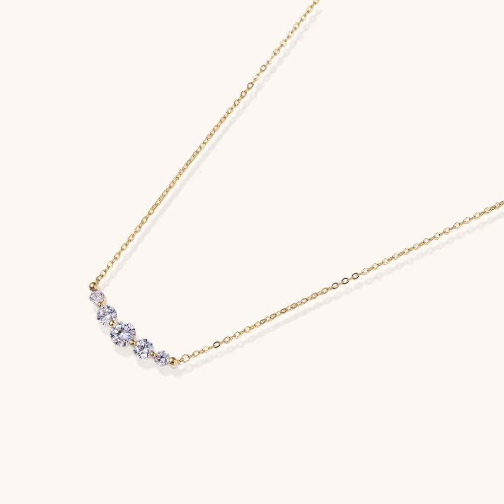 Delicate 14K gold-plated necklace with five graduated zirconia stones arranged in a curved arc on fine chain